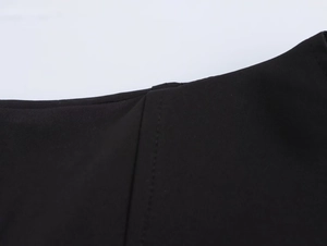 Detailed macro view of high-quality stitching and crepe fabric texture on black dress