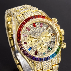 Macro shot of gold tone luxury watch with rainbow gemstone bezel and iced out diamond case