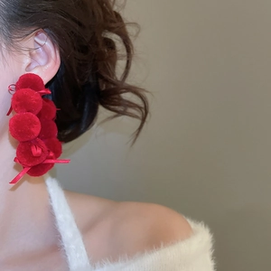 Detail view of red velvet ball hoop earrings with delicate ribbon bows on a model