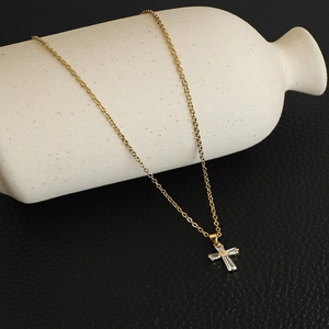 Detail of gold cross pendant with baguette-cut zirconias on a fine stainless steel chain