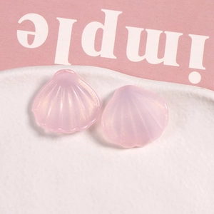 Primer plano de dos colgantes de resina rosa en forma de abanico con sutil brillo dorado
