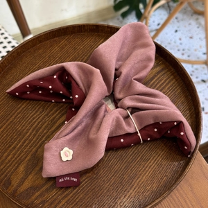 Close-up of pink polka dot scrunchie with a white flower button on a wooden tray