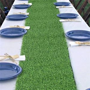 Close-up macro view of green artificial grass table runner on a long outdoor wooden table