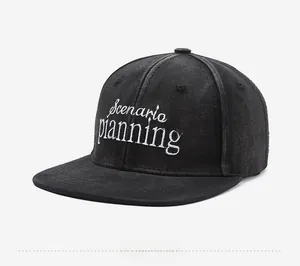 Close-up of Scenario planning white embroidery on a black washed denim flat brim cap