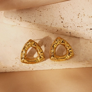 Detailed view of golden triangle stud earrings with irregular lava hammered texture on silk