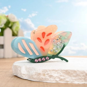 Detailed view of colorful butterfly hair claw clip with rhinestones on a stone base