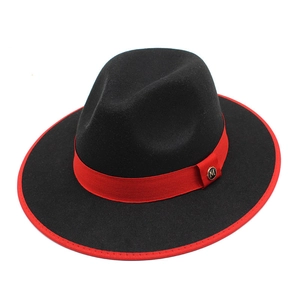 Detail of black wool fedora featuring a red ribbon band and golden M-letter badge