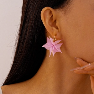 Detail of pink acrylic flower earrings with gold metal rings worn by a model