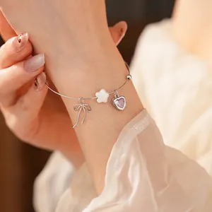 Silver bracelet with bow, star and pink heart stone pendant on woman's wrist