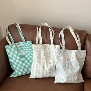 Detailed view of three cotton tote bags with floral and checkered prints on a leather sofa