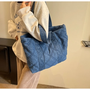 Gros plan du sac cabas en jean bleu matelassé montrant les surpiqûres et la texture denim