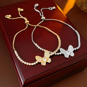 Détail de bracelets papillon ajustables en zircon doré et argenté sur un coffret
