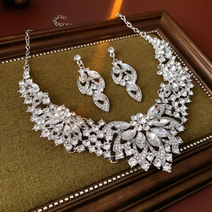 Macro shot of silver flower necklace and earring set with crystals on green velvet