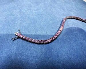 Dettaglio del bracciale tennis con pietre rosa taglio rotondo su fondo blu