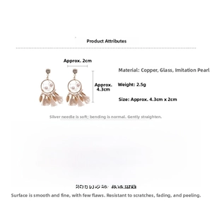 Macro detail of gold pearl tassel earrings with circular woven frame and silver needles