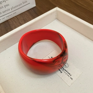 Detailed shot of an irregular red marble resin bangle on a minimalist display tray
