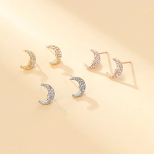 Detailed view of crescent moon stud earrings with pavé cubic zirconia in three metal tones