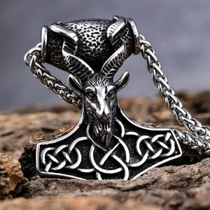 Vintage stainless steel Mjölnir pendant with ram head on rustic wood background