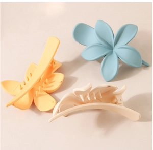 Trois pinces à cheveux fleur mates en bleu, jaune et beige sur fond rose doux