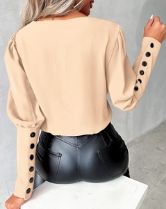 Close-up of elegant button cuffs on warm beige long sleeve blouse for women