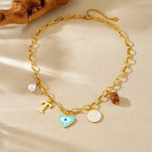 Collier en acier doré avec pendentifs oeil protecteur, coeur et perle sur sable fin