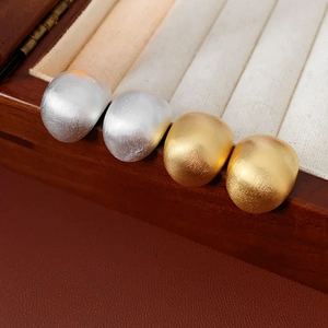 Nahaufnahme von mattierten Ohrsteckern in Gold und Silber in einer Schmuckschatulle
