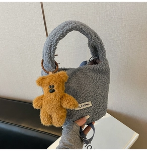 Blue lamb wool bucket bag featuring a cute brown plush bear charm and brand logo tag