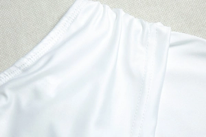 Detailed close-up of double-stitched seams on white elastic fabric dress