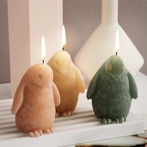 Drei realistische 3D-Pinguin-Duftkerzen mit Federmuster auf einer Wellenbasis