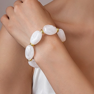 Macro detail of acrylic marble oval beads and gold spacer rings on a fashion bracelet