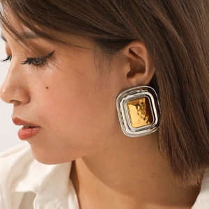 Macro detail of geometric two-tone hammered texture earrings worn by a model