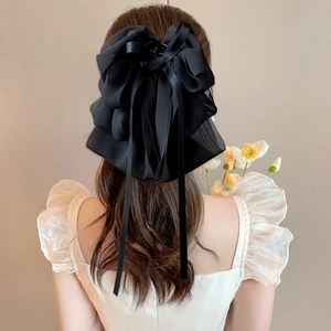 Detail of elegant black layered tulle bow hair claw clip with long flowing ribbons