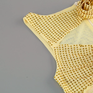 Détail de robe en maille jaune avec strass dorés et ornements de fleurs plissées