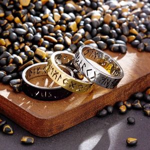 Trois bagues de runes vikings en argent, or et noir sur fond de bois rustique chic