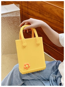 Detail der gelben EVA Strandtasche mit einem niedlichen orangefarbenen Blumen-Accessoire
