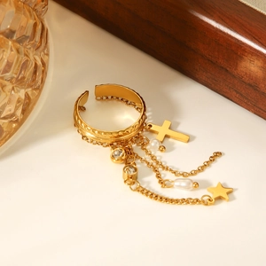 Close-up of gold adjustable ring featuring cross, star, and pearl charms on a surface