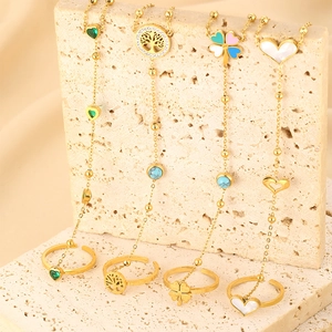 Detail von vier vergoldeten Edelstahl-Herz- und Lebensbaum-Ring-Armband-Sets