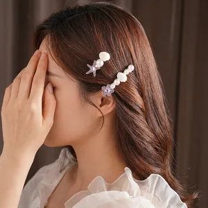 Set de barrettes élégantes avec étoile de mer, coquillage, perles et strass violets sur modèle