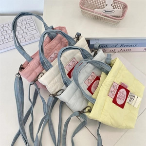 Détail de mini sacs matelassés avec motifs cœurs et patchs cerise sur un bureau blanc