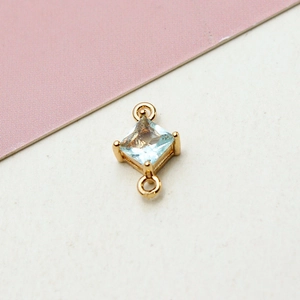 Detail of gold-plated geometric rhombus connector with light blue zircon and dual loops