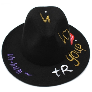 Detail of black wool fedora featuring hand-painted graffiti symbols and gold lettering