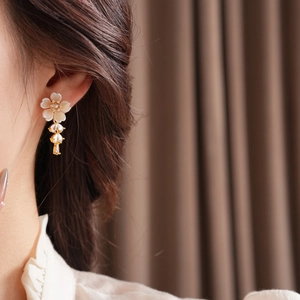 Detailed close-up of a model wearing gold flower earrings with teardrop zircon tassels