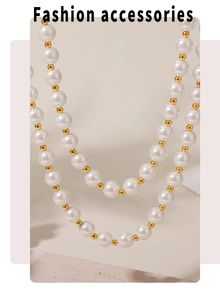 Detail of 12mm shell pearl and gold bead layered necklace on a textured stone base