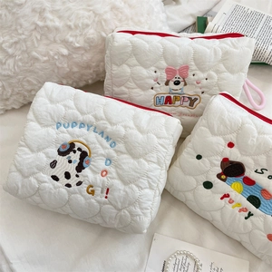 Detail of cute puppy embroidery on a quilted white heart pattern makeup bag with red zipper