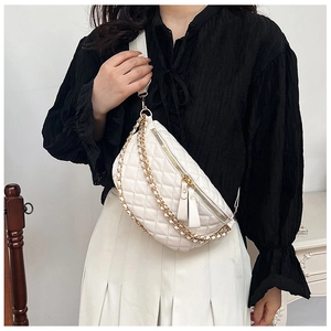 Detail of white quilted crossbody bag with gold chain and woven strap on model