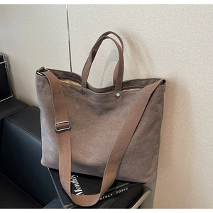 Detail of taupe canvas tote bag with dual handles and long strap in a lifestyle setting