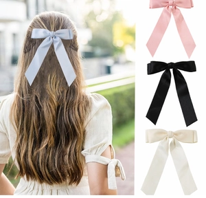 Detail of satin bow hair clips in light blue pink black and beige showing ribbon texture