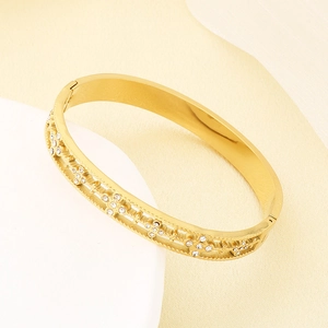 Detailed close-up of 18K gold plated bangle featuring hollow cross patterns and white zircons