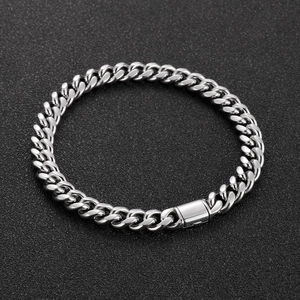 Macro shot of silver Cuban link bracelet with square clasp on textured grey background