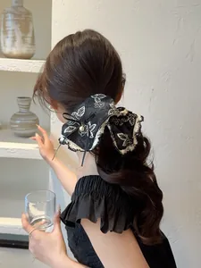 Detail of elegant black floral scrunchie with lace edges and a pearl pendant charm